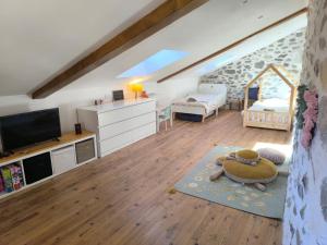 a living room with a tv and a room with a couch at Fajureya House in Vaumeilh
