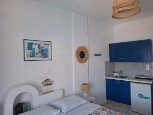 a kitchen with blue cabinets and a bed in a room at Vrahos Rooms - Studios in Alopronia +159 photos