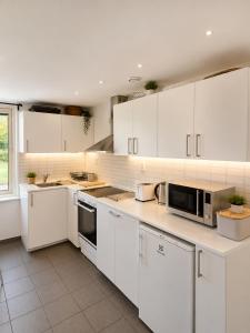 a white kitchen with white cabinets and appliances at Nordic Home Finja in Hässleholm +6 photos