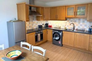 a kitchen with wooden cabinets and a table with a dishwasher at Charming Lisburn Flat with private parking in Lisburn
