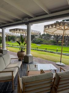 a patio with couches and a table and an umbrella at The Fairway Apartment in Plettenberg Bay