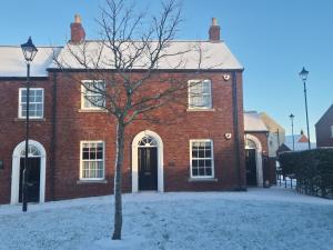 a red brick building with a tree in the snow at Charming Lisburn Flat with private parking in Lisburn +1 photo