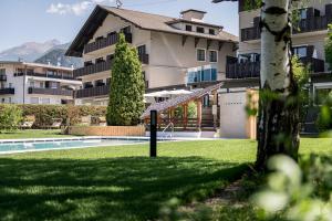 ein Gebäude mit einem Hof mit einem Swimmingpool in der Unterkunft Hotel ANDER in Bruneck