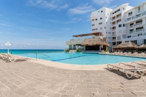 ein Schwimmbad vor einem Gebäude mit Blick auf das Meer in der Unterkunft Suites Sol y Luna in Cancún