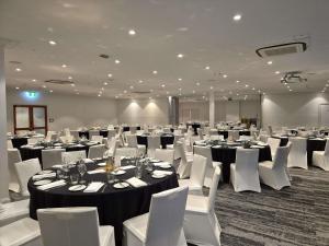 a large room with tables and white chairs and tablesearcher at Mercure Canberra in Canberra