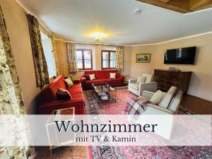 a living room with red couches and a tv at VILLA SEEBERG - by "Schloss Gessenberg" luxurious vacation home with lake and mountain views, suitable for families and friends in Petting