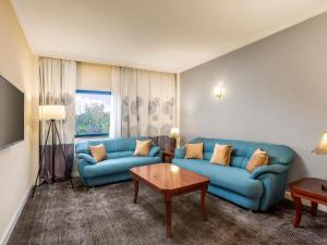 a living room with blue couches and a table at Novotel Port Harcourt in Port Harcourt