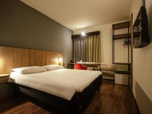 a hotel room with a large bed and a desk at ibis Betim in Contagem