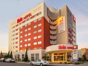 a hotel with cars parked in front of it at ibis Caxias do Sul in Caxias do Sul