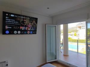 a living room with a tv and a sliding glass door at Marzan Playa in Foz