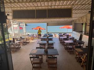 a restaurant with tables and chairs and the beach at Pousada Amendoeira in Mangaratiba +65 photos