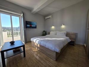 a bedroom with a large bed and a large window at Kos Harmony Apartments in Kefalos
