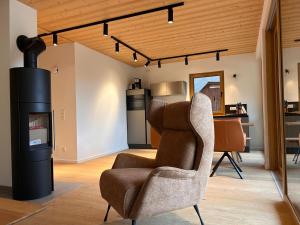 a living room with a chair and a stove at NockLodge Sankt Oswald in Bad Kleinkirchheim