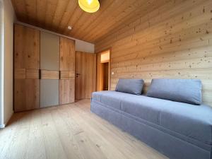 a bedroom with a blue couch in a wooden wall at NockLodge Sankt Oswald in Bad Kleinkirchheim