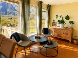 a living room with three chairs and a large window at KB - Waterfront Villa Sørvågen in Moskenes