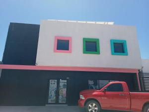 a red truck parked in front of a building with four windows at Suits hotel boutique in Nuevo Casas Grandes