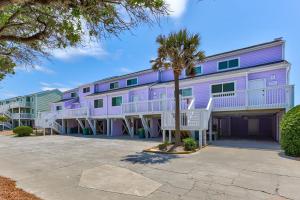 a purple building with a palm tree in front of it at Three Little Birds in Kure Beach