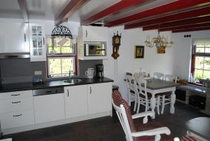 een keuken met witte kasten en een tafel met stoelen bij Vakantiehuis "It koaihûs" in Jistrum