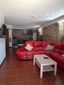 a living room with a red couch and a table at CabrilHome - AL Gerês in Cabril