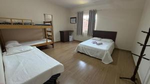 a room with two beds and a bunk bed at Pousada Amendoeira in Mangaratiba
