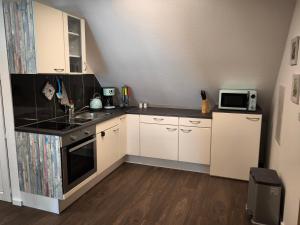a small kitchen with white cabinets and a microwave at Ferienwohnung Weyer in Villmar