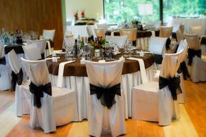 a group of tables with white chairs with black bows at Viešbutis "Linelis" in Paplatelė