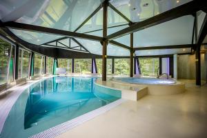a large swimming pool in a building with a large window at Viešbutis "Linelis" in Paplatelė