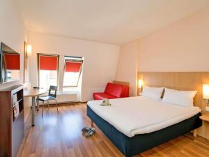 a hotel room with a large bed and a red chair at ibis Berlin City Süd in Berlin