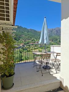 a patio with a table and an umbrella at CabrilHome - AL Gerês in Cabril