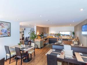 a restaurant with tables and chairs and a kitchen at Hotel Mercure Rennes Cesson in Cesson-Sévigné