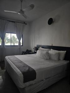 a bedroom with a large white bed with a window at Casa del Viento Celestun in Celestún