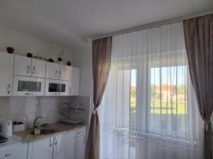 a kitchen with a window with curtains and a sink at Apartman ISKRA in Mataruška Banja