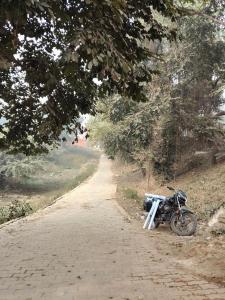 a motorcycle parked on the side of a dirt road at Mauni Ashram in Prayagraj
