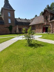 a building with a grass yard with a umbrella at Le Sart de Bouland in Frasnes-lez-Anvaing