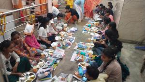 a group of people sitting on the floor eating food at Mauni Ashram in Prayagraj