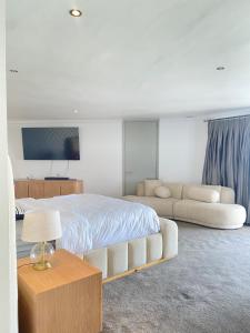 a bedroom with a large bed and a couch at De Ocean Lane Guest House in Cape Town