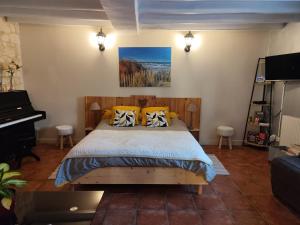 a bedroom with a bed with yellow pillows and a piano at Petit havre de tranquillité in Loudun +16 photos
