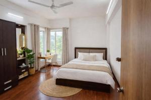 a bedroom with a bed and a desk and a window at Velora Stays - Nr Airport & World trade center in Pune