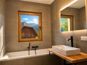 a bathroom with a tub and a sink and a window at NockLodge Sankt Oswald in Bad Kleinkirchheim +34 photos