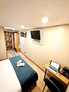 a bedroom with a bed and a desk with a laptop at Logis Hôtel & Restaurant Cap Hôtel in Noyelles-Godault