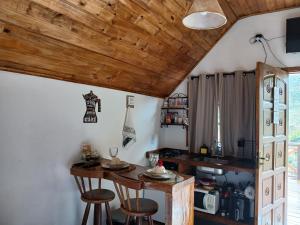 a kitchen with a table and stools in a room at Chalé 2 com hidromassagem in Camanducaia