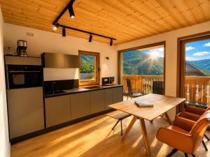 a kitchen and dining room with a table and a view at NockLodge Sankt Oswald in Bad Kleinkirchheim