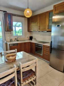 a kitchen with wooden cabinets and a table and a refrigerator at Zoe By The Sea in Paralia Katerinis