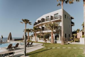 a building with palm trees and a swimming pool at Renieris Hotel in Stalos