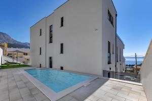 a large white building with a swimming pool on a patio at Apartman A Villa Legato in Tučepi
