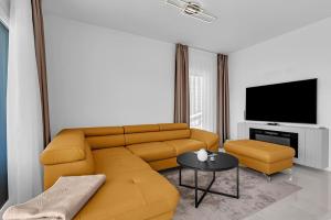 a living room with a yellow couch and a tv at Apartman A Villa Legato in Tučepi