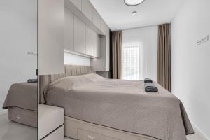 a white bedroom with a bed and a mirror at Apartman A Villa Legato in Tučepi +6 photos