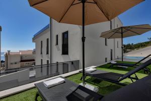 a balcony with two chairs and two umbrellas at Apartman A Villa Legato in Tučepi