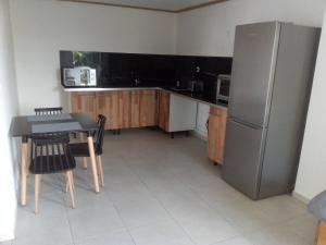 a kitchen with a refrigerator and a table and chairs at Le petit coin de campagne in Le Robert