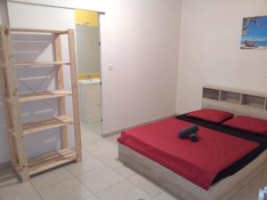 a small bedroom with a bed with a red blanket at Le petit coin de campagne in Le Robert